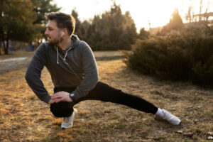 Man stretching outdoors during a workout at sunset, representing healthy movement, recovery, physical activity, and lifestyle habits commonly discussed in peptide weight loss therapy and wellness programs.